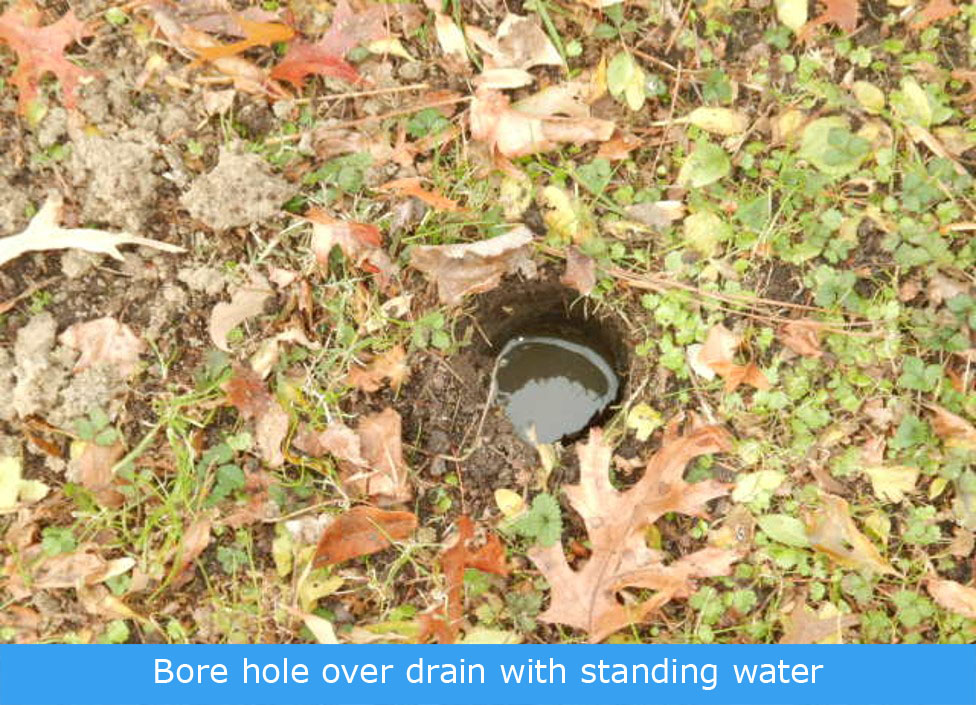 small bore hole over the drain line with standing water inside the hole