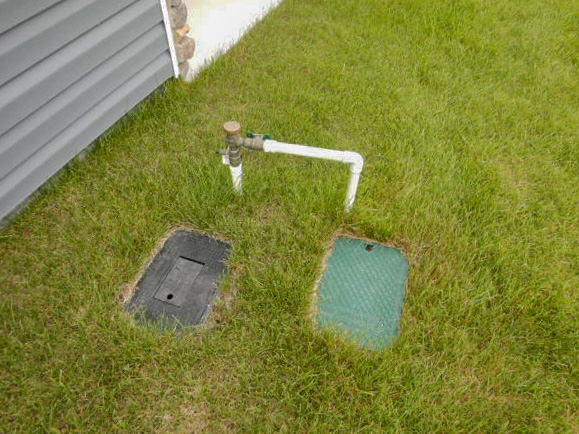 green and black control valve covers in the ground