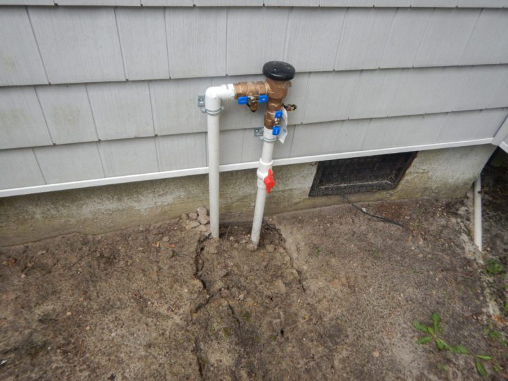 White PVC pipes going underground beside a house