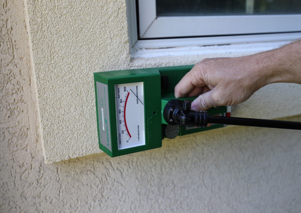 Man placing a green inspection device outside a window