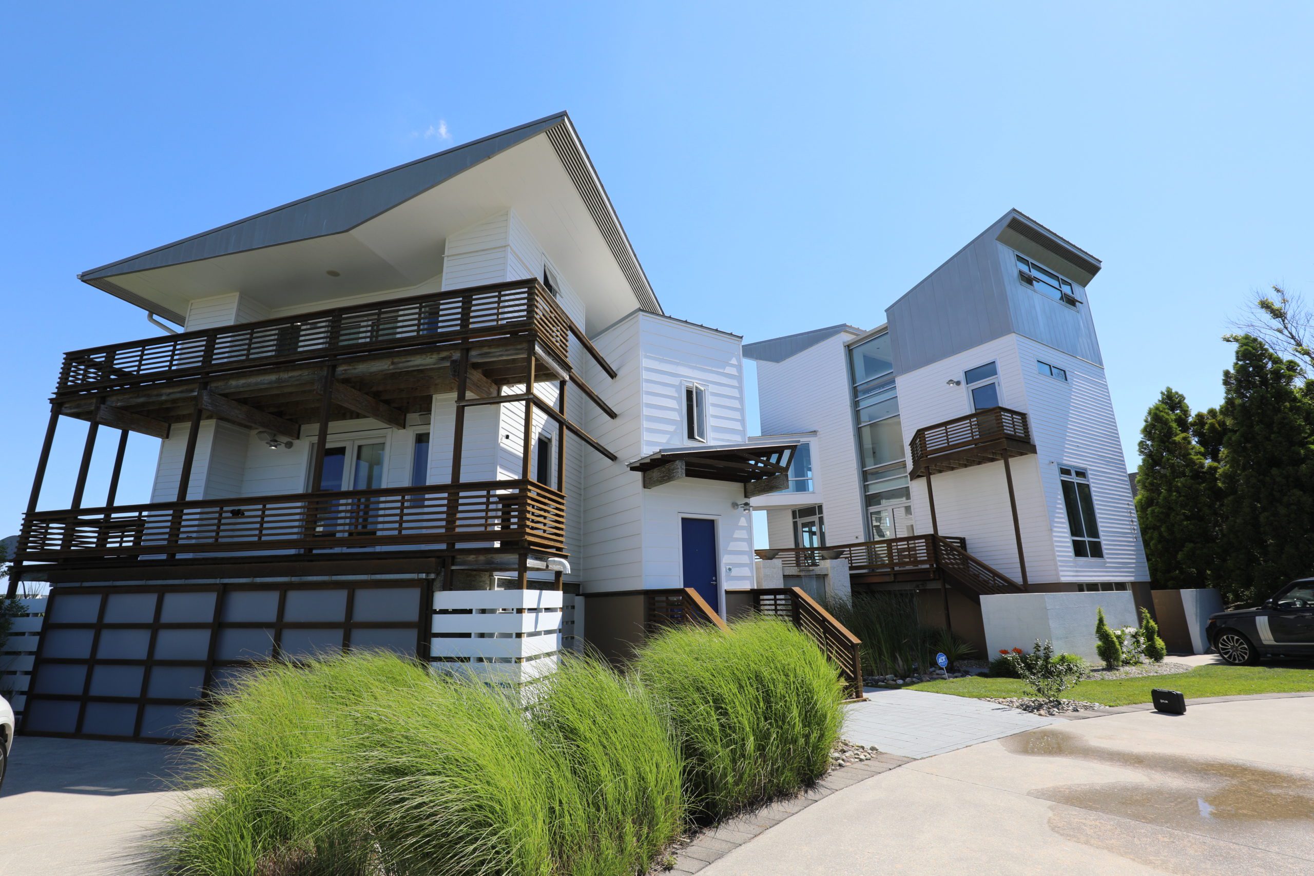 modern white house with wood balconies and dune grass