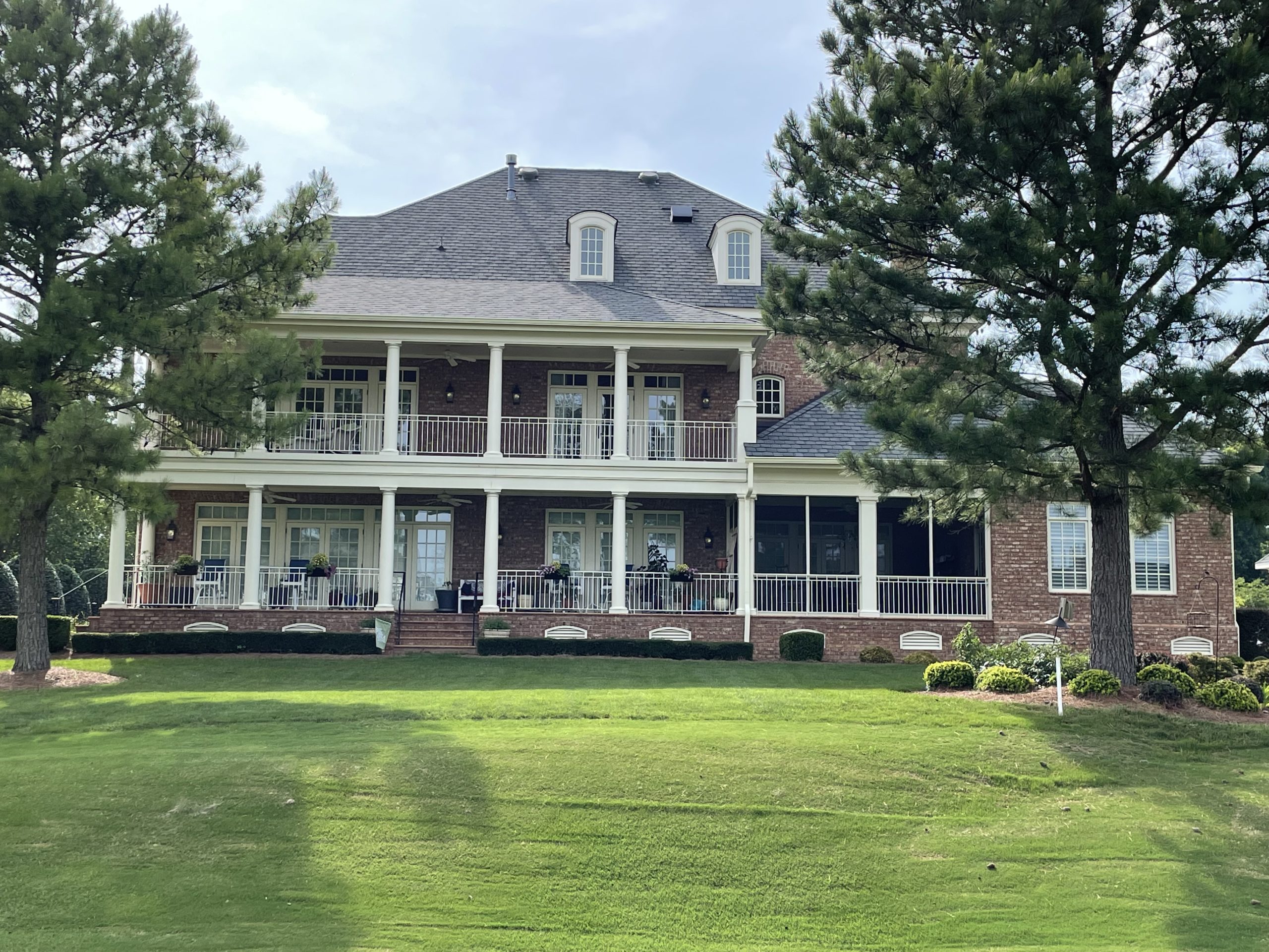 back of a large brick house with porch and balcony